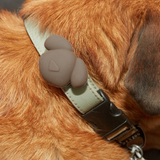 Close-up of a dog's collar with a soft toy attached on a brown fur background